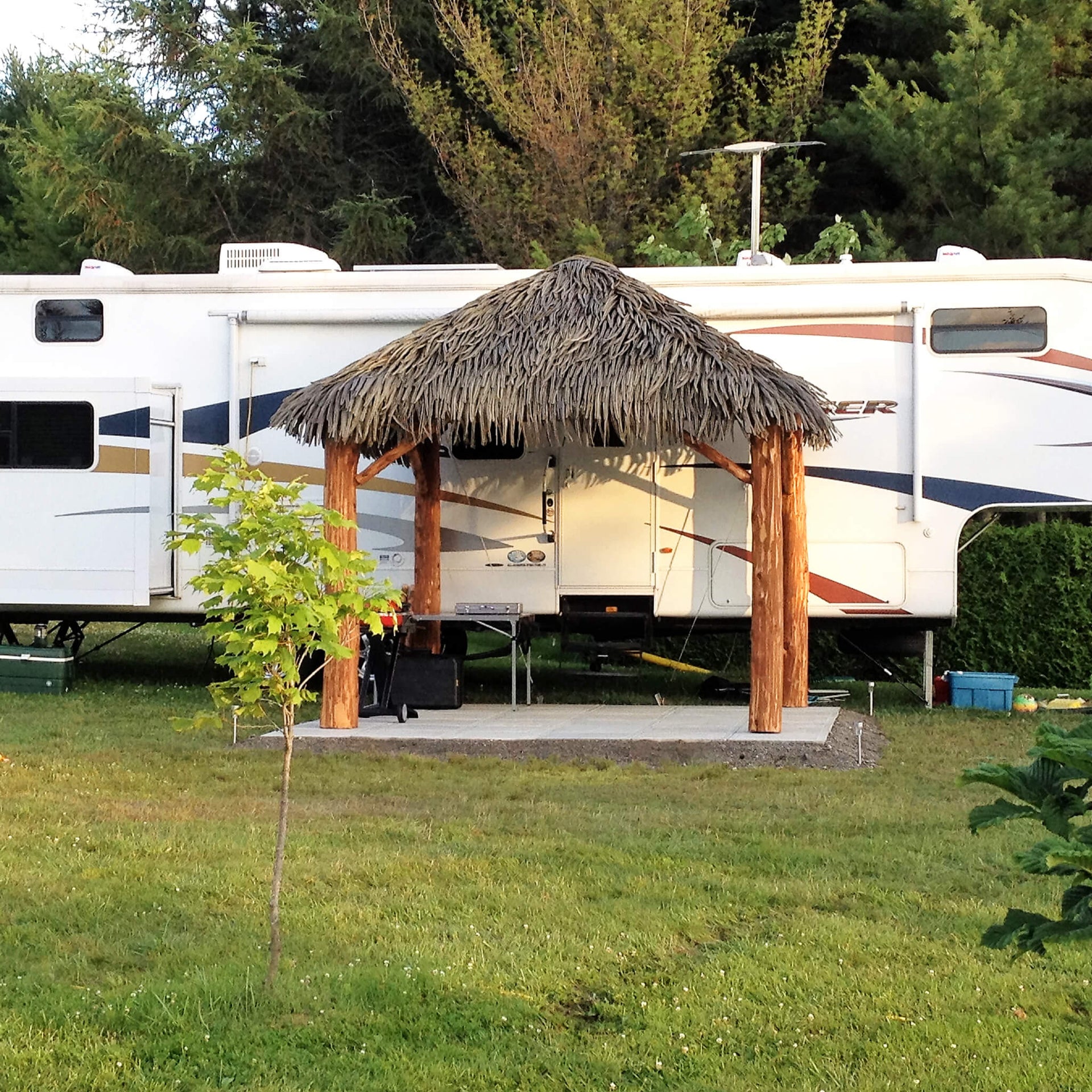 Gazebo en bois avec toiture en feuilles de palmier synthétiques Palmita dans un camping - Boutique Palmex